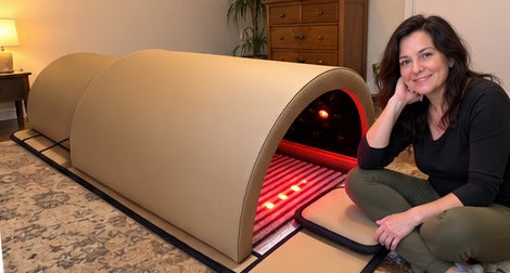 The Restore Dome on a living-room floor with a woman sitting beside it