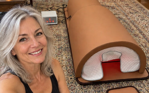The Restore Dome on a living-room rug with a woman sitting beside it and the controller nearby