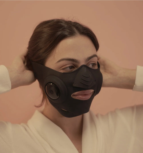 InstaLift EMS Mask worn by a model, hands behind her head, three-quarter view
