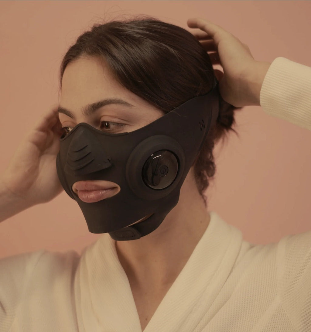 InstaLift EMS Mask worn by a model, adjusting the strap, side view