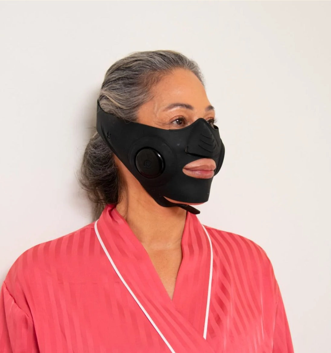 InstaLift EMS Mask on a silver-haired model in a pink robe, three-quarter view