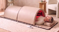 The Restore Dome™ full-body infrared sauna in a bright living room, head resting outside the larger dome section